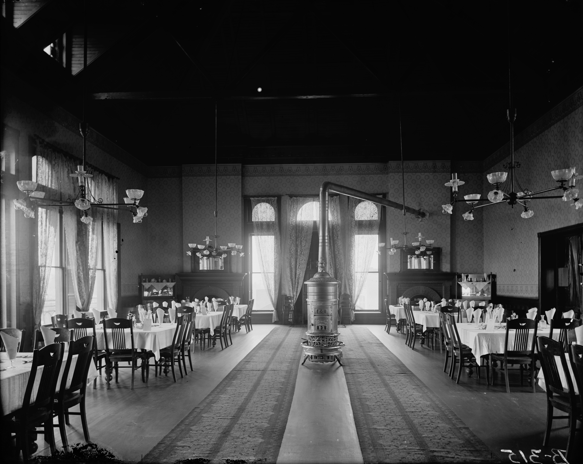 1890s Natchez Hotel dining room with combination gas and electric chandeliers hanging above tables
